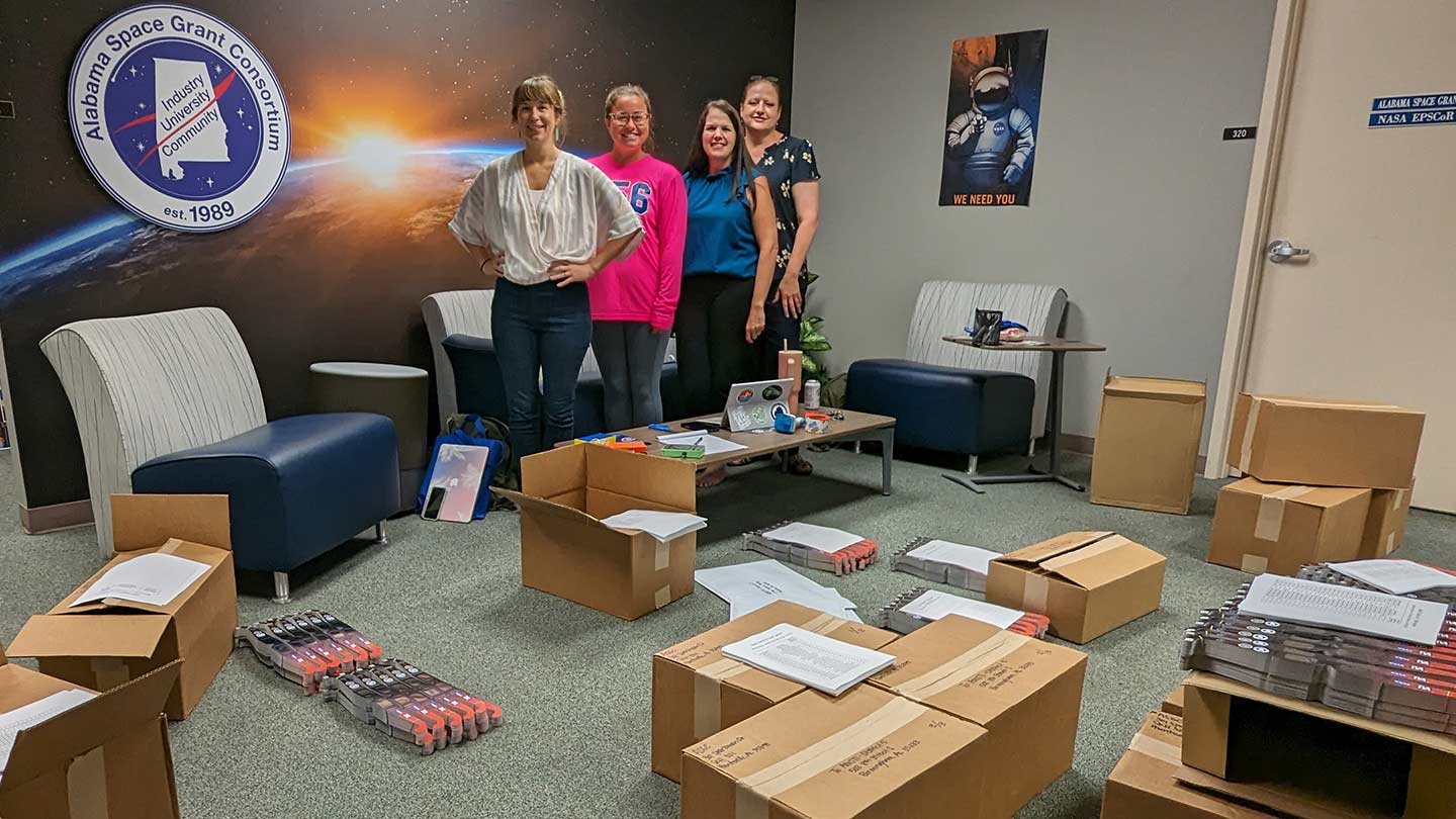 ASGC team in a room full of boxes filled with solar glasses.