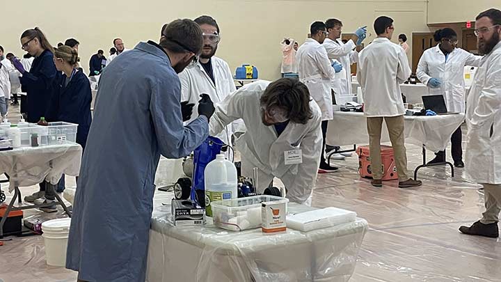 students in coats surround chemical engineering equipment ?>