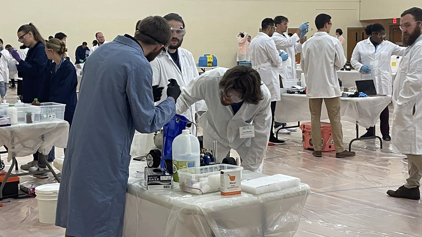 students in coats surround chemical engineering equipment