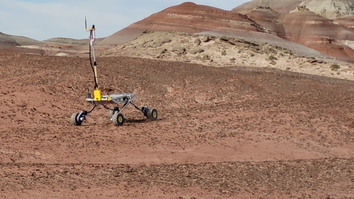 a rover in the desert with red rock formations in the background