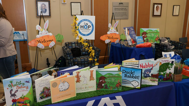 A colorful display of children's books on a table, decorated with bunny-themed signage and a welcoming atmosphere.