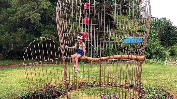 little girl sitting in a giant birdcage