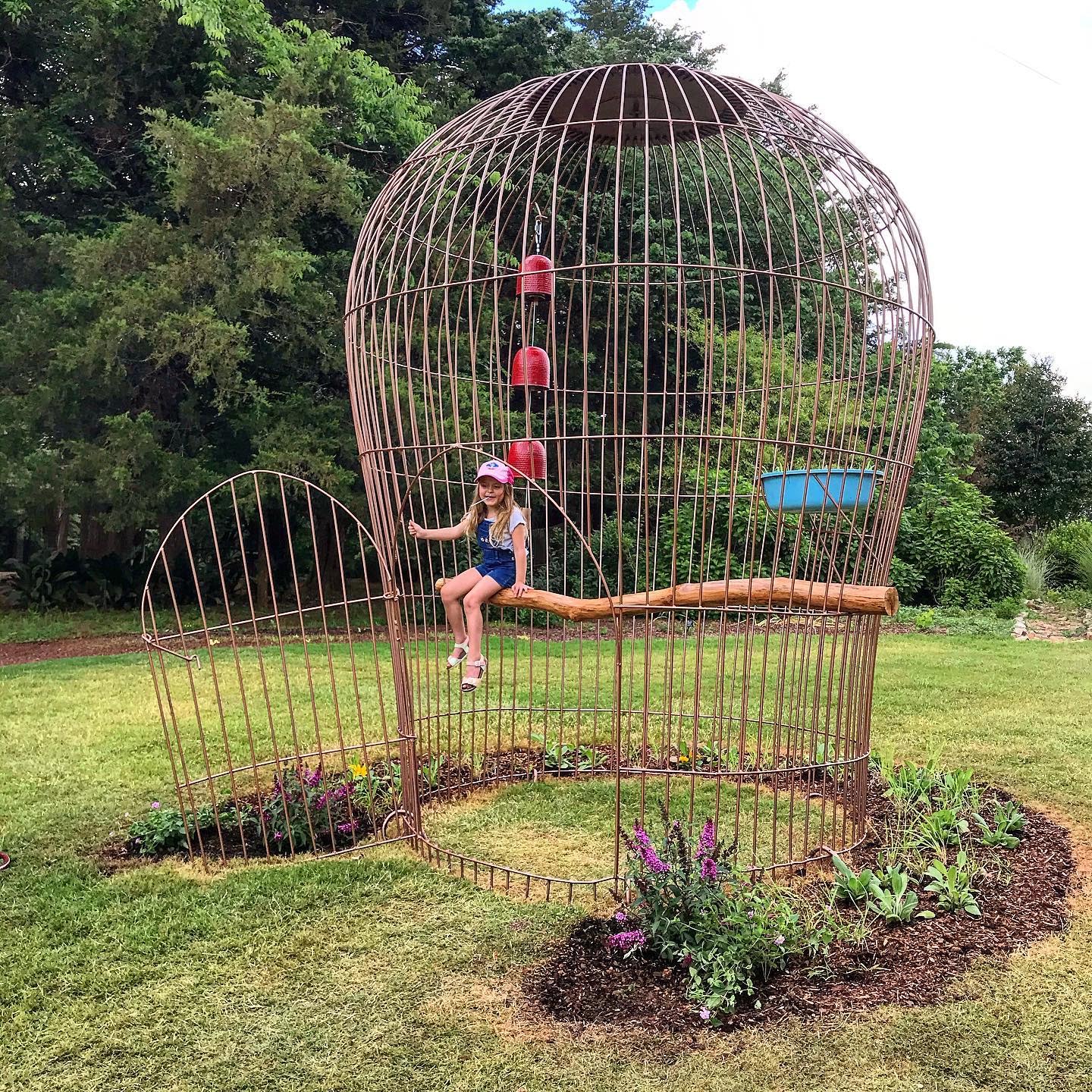 little girl sitting in a giant birdcage