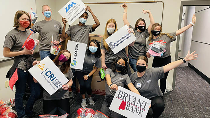 Students pose with sponsor signs after UAH Big Event service day