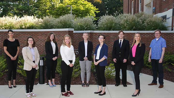 INCLUDE team posing outside at UAH in front of a brick wall. ?>