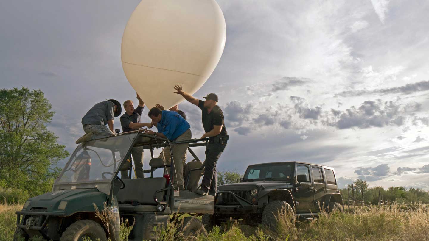 Five people standing on an offroad vehicle maneuvering a surveillance balloon on Skinwalker Ranch