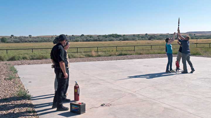 Five people prepare a rocket for launch.