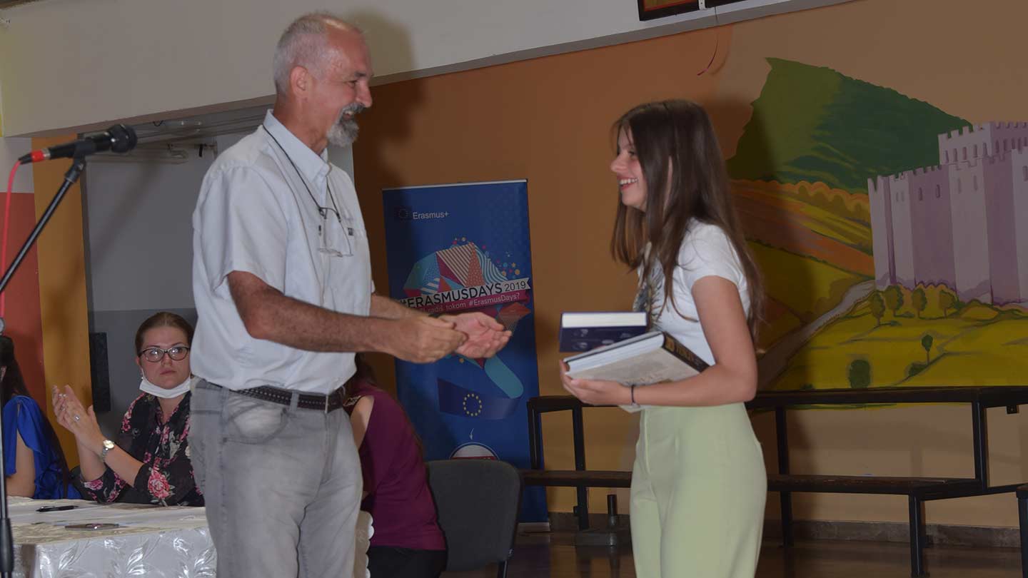 Emil Jovanov handing a student a book.