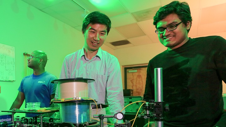 Duane and Hoque smiling and looking at their experiment in their UAH laboratory