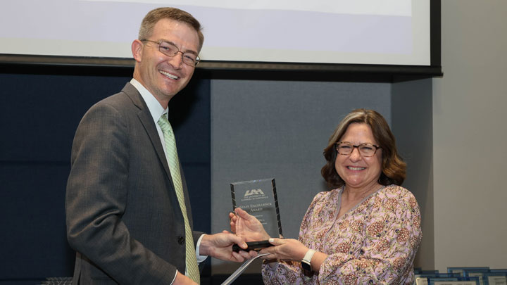 Brad Cooper, assistant vice president, finance and business services/controller, presents Staff Excellence Award to Rae Gill