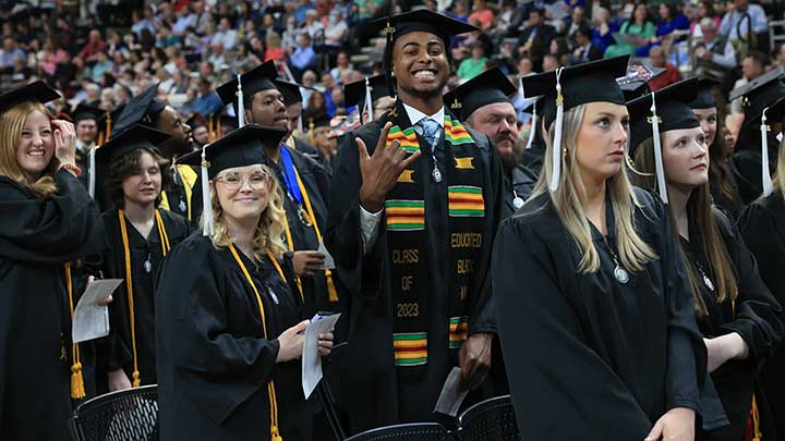 gradute students at graduation in cap and gowns. ?>