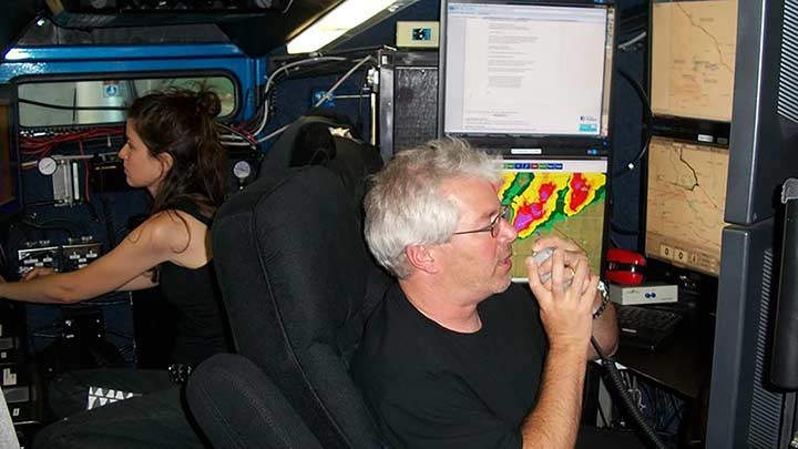 Two people monitoring data and weather monitors.