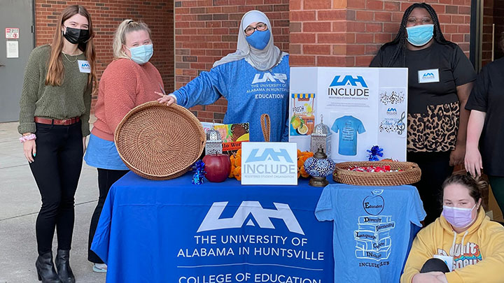 photo of INCLUDE club members gathered around an outdoor booth ?>