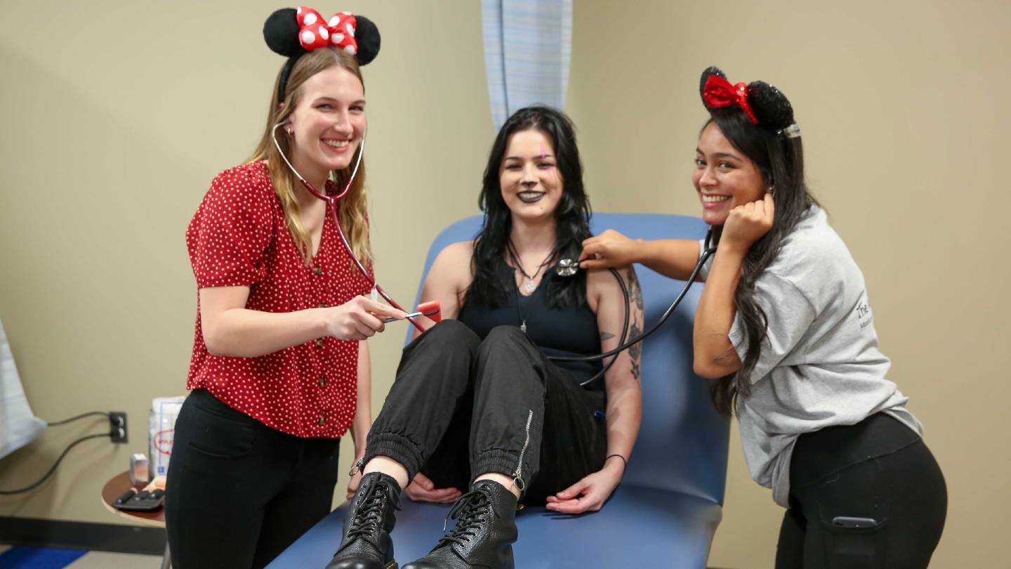 3 smiling girls pretending to be in a hospital - one as as a patient and two as nurses or doctors