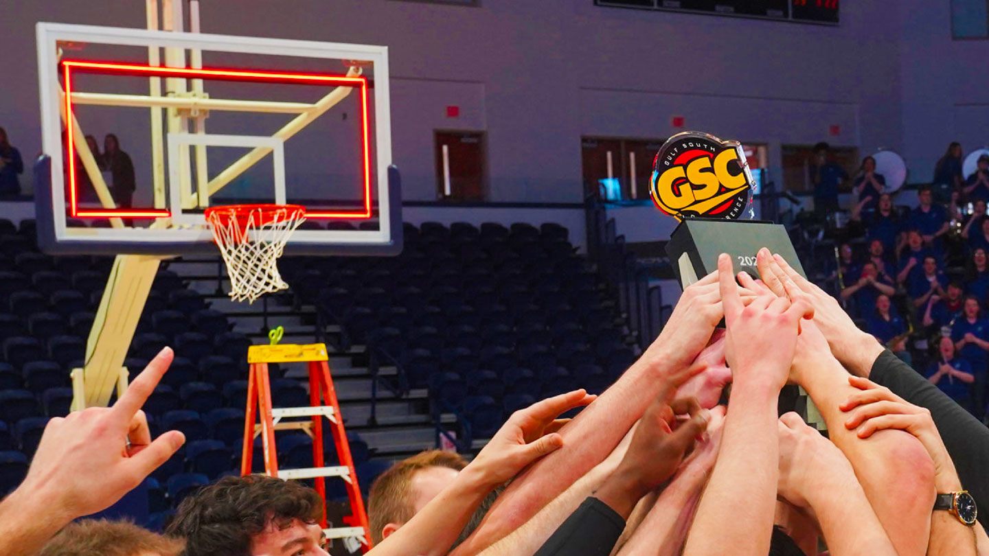 Members of the U A H men's basketball team hold aloft a conference championship trophy.