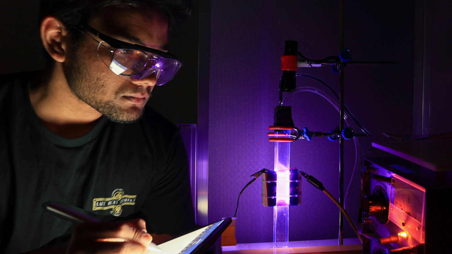 A U AH graduate student makes observations and takes notes during a plasma experiment.