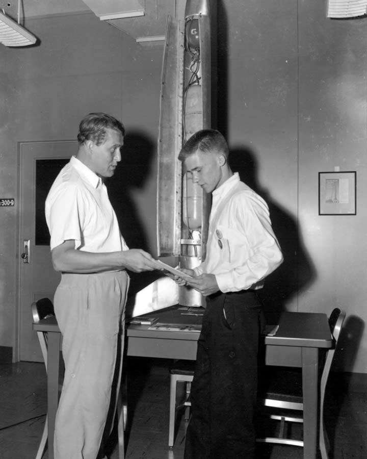 Dr. Wernher von Braun shares technical papers with 17-year-old Jimmy Blackmon at Redstone Arsenal in front of the rocket Blackmon built in his basement