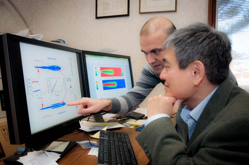 Doctoral candidate Omid Samimi, left, and Dr. C. P. Chen discuss their computer simulation of evaporating fuel sprays.