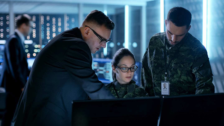 Military persons working on computers together ?>