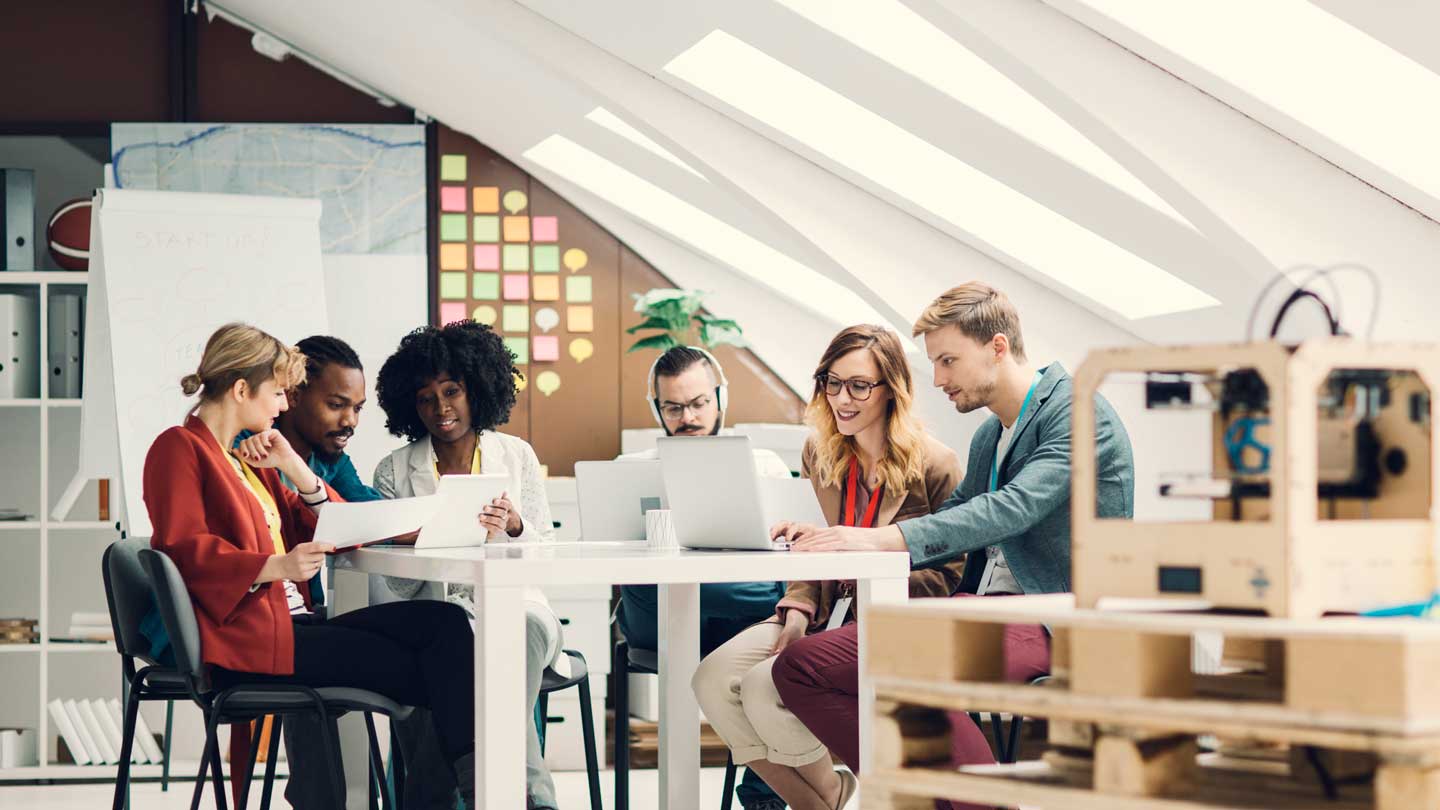 A group of people sitting around a table brainstorming ?>