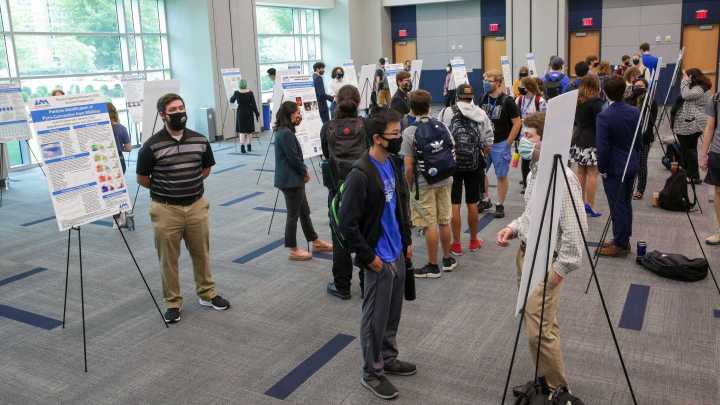 People looking at posters on display inside building.