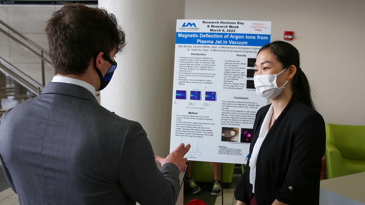 students discussing a research poster on display