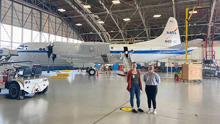 Shelby Bagwell and Ashlyn Shirey stand infront of a P-3 Aircraft ?>