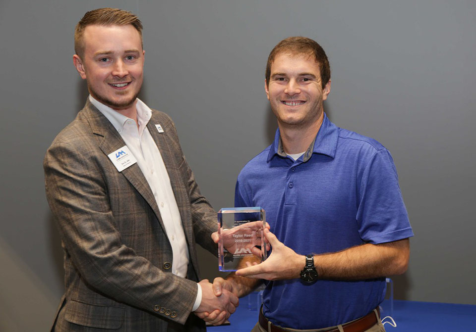 Photo of Eric St. John and Taylor Reed exchanging a recognition award.