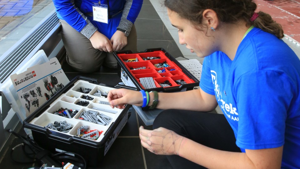 girl studies lego pieces organized in a kit box