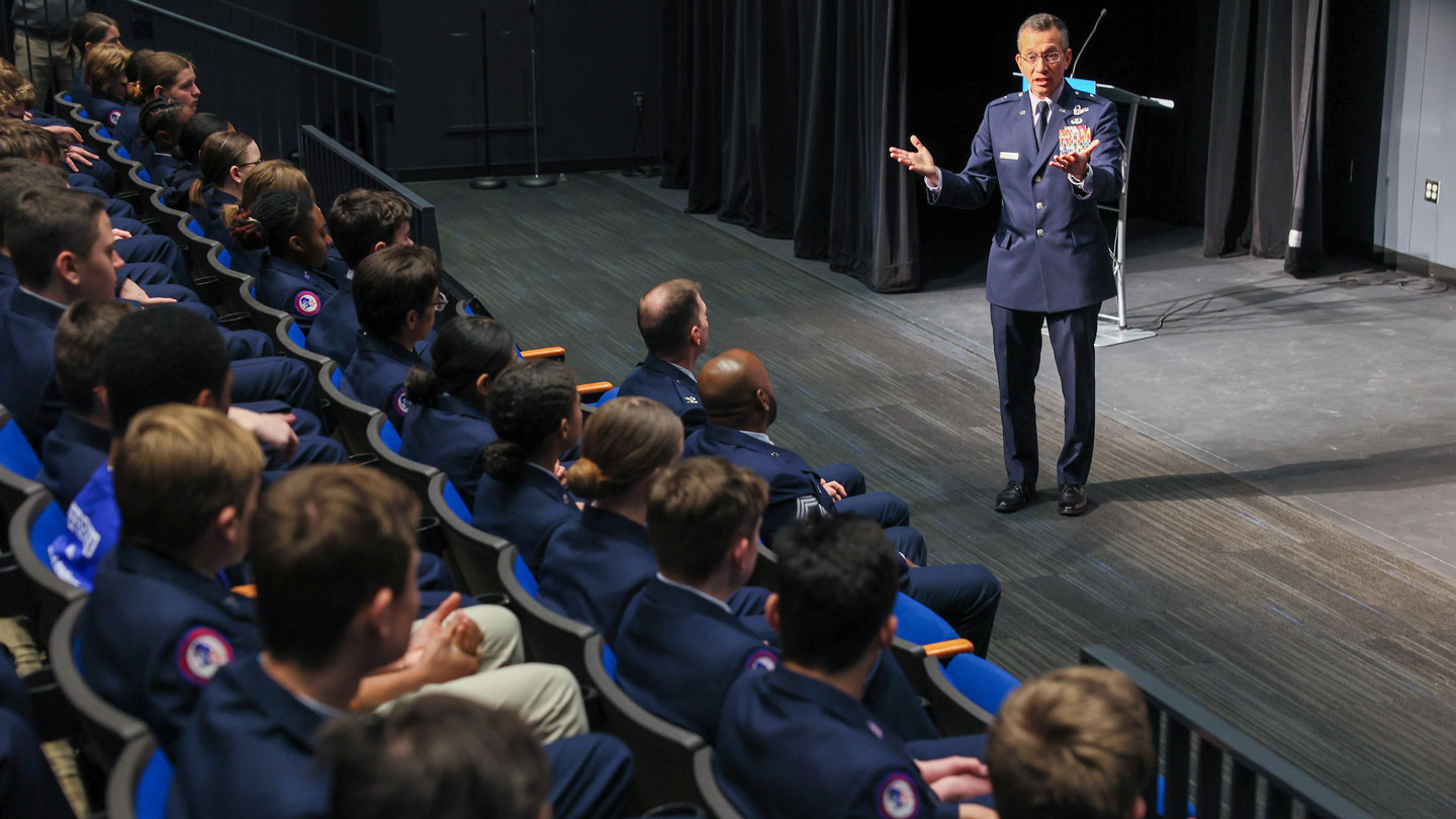 People in auditorium listening to a speaker on stage