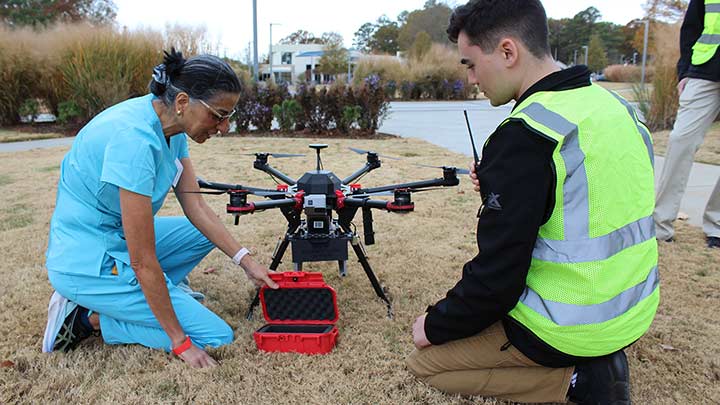 Two people working on a drone in the grass.