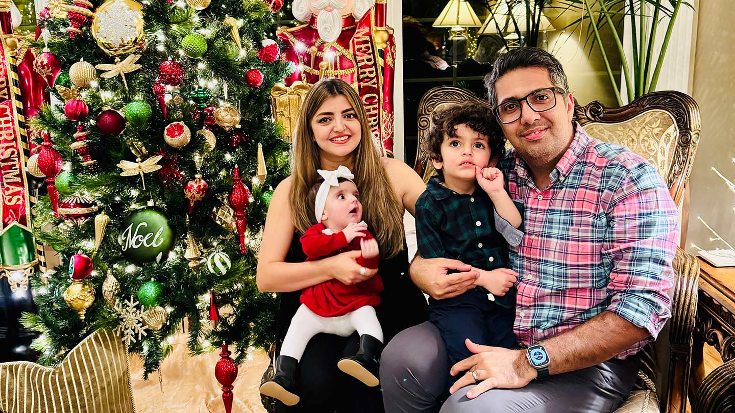 Armin Ahmadi Gelayol Mohammadnazar and their two yound children smiling in front of a Christmas Tree