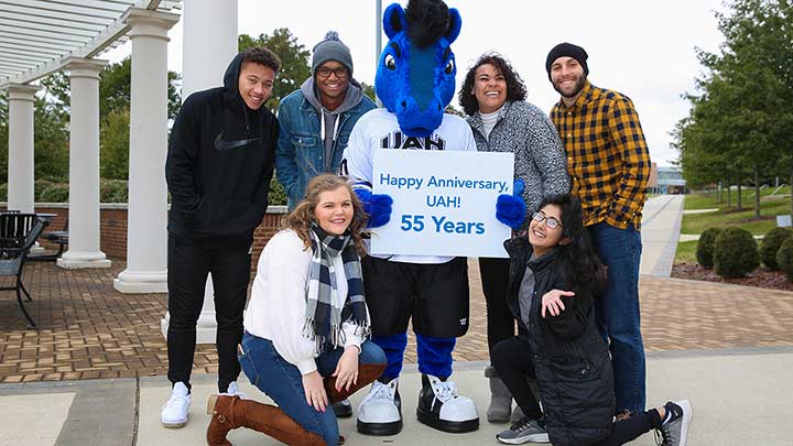 Students posing outside with UAH mascot.
