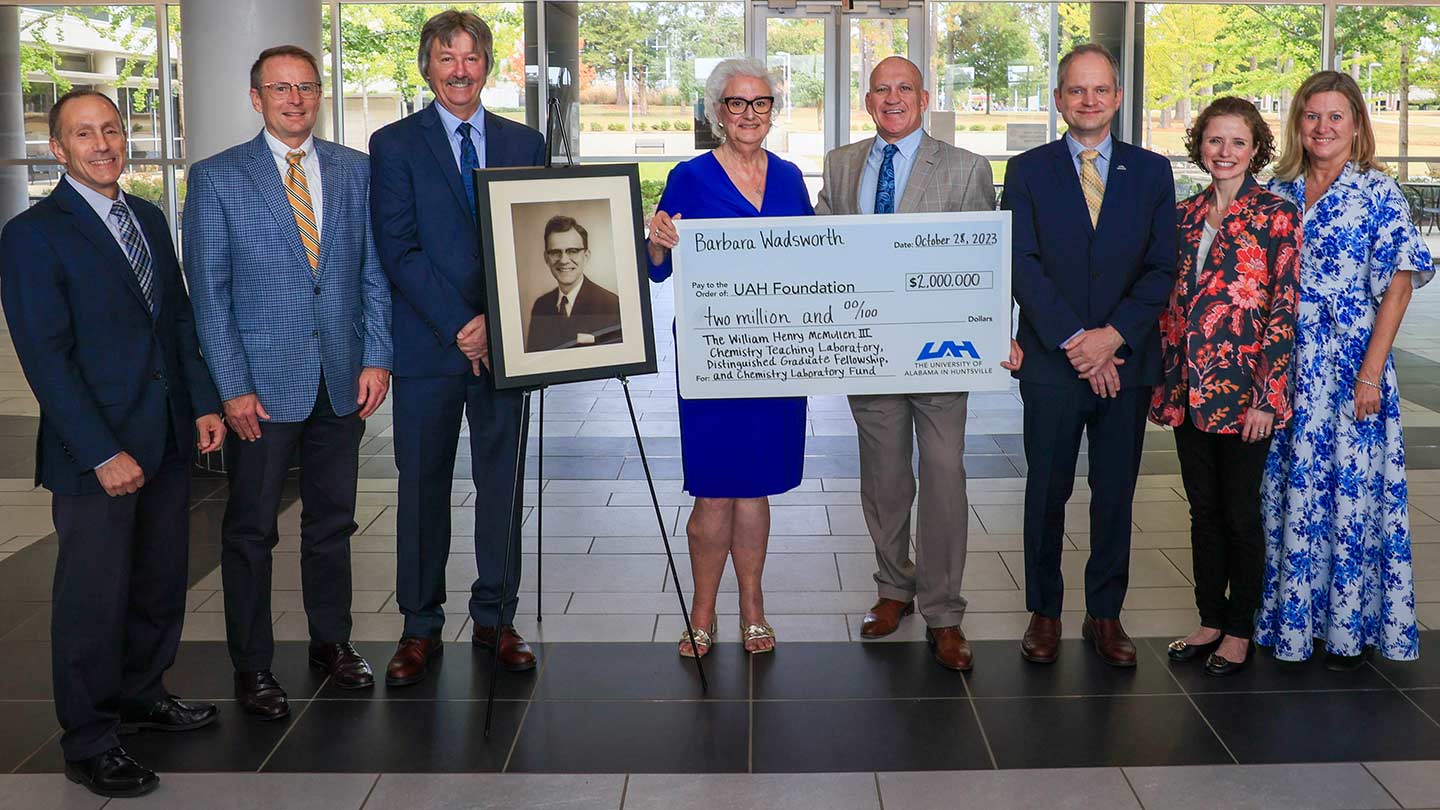 People posing holding a giant check.