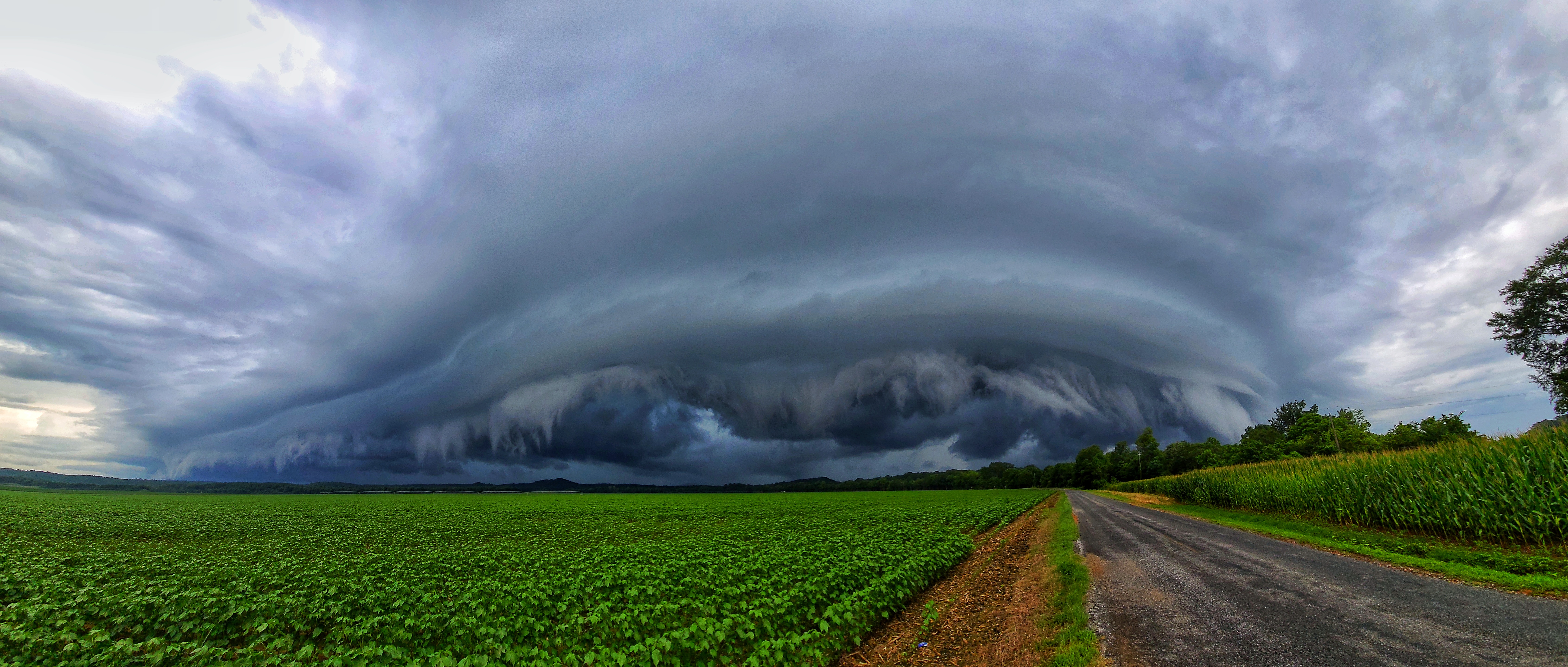 Large rotating supercell storm over farmland with dramatic cloud structure.