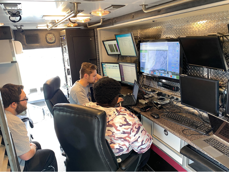 UAH AES undergraduate students Caleb Kiser (left) and Michael Yurovchak (back) and graduate student Mariama Feaster (center) examining weather observations taken by UAH ESSC SWIRLL MAPNet Facilities Research vehicle. Courtesy Preston Pangle. ?>