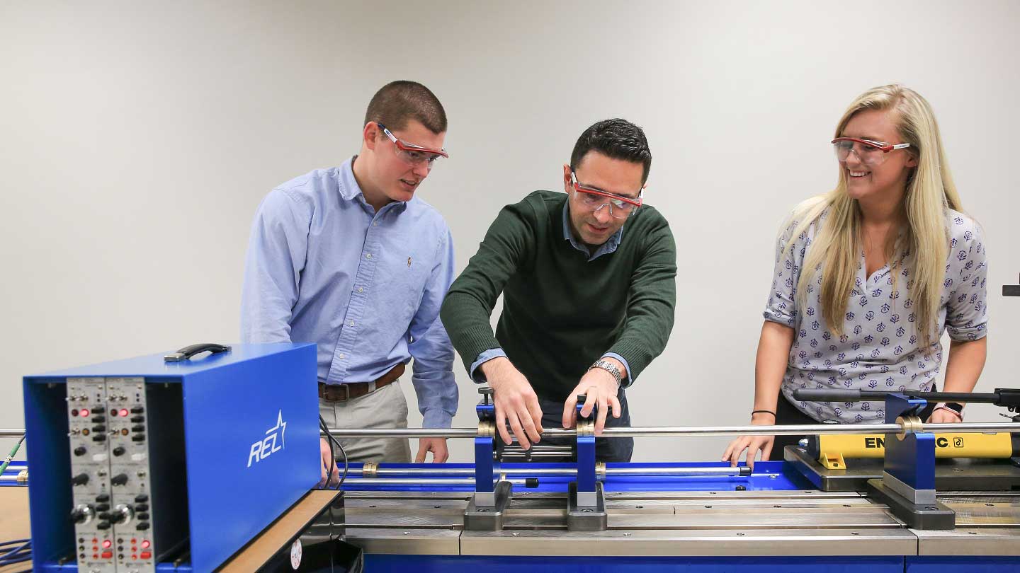 three people operate a long technical device