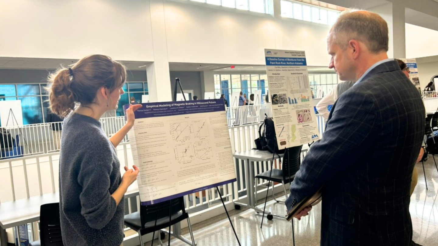 UAH physics major Sophia Vanderwaal, discusses her reserach on pulsars as galactic accelerometers with Dr. Rainer Steinwandt, Dean, UAH College of Science.